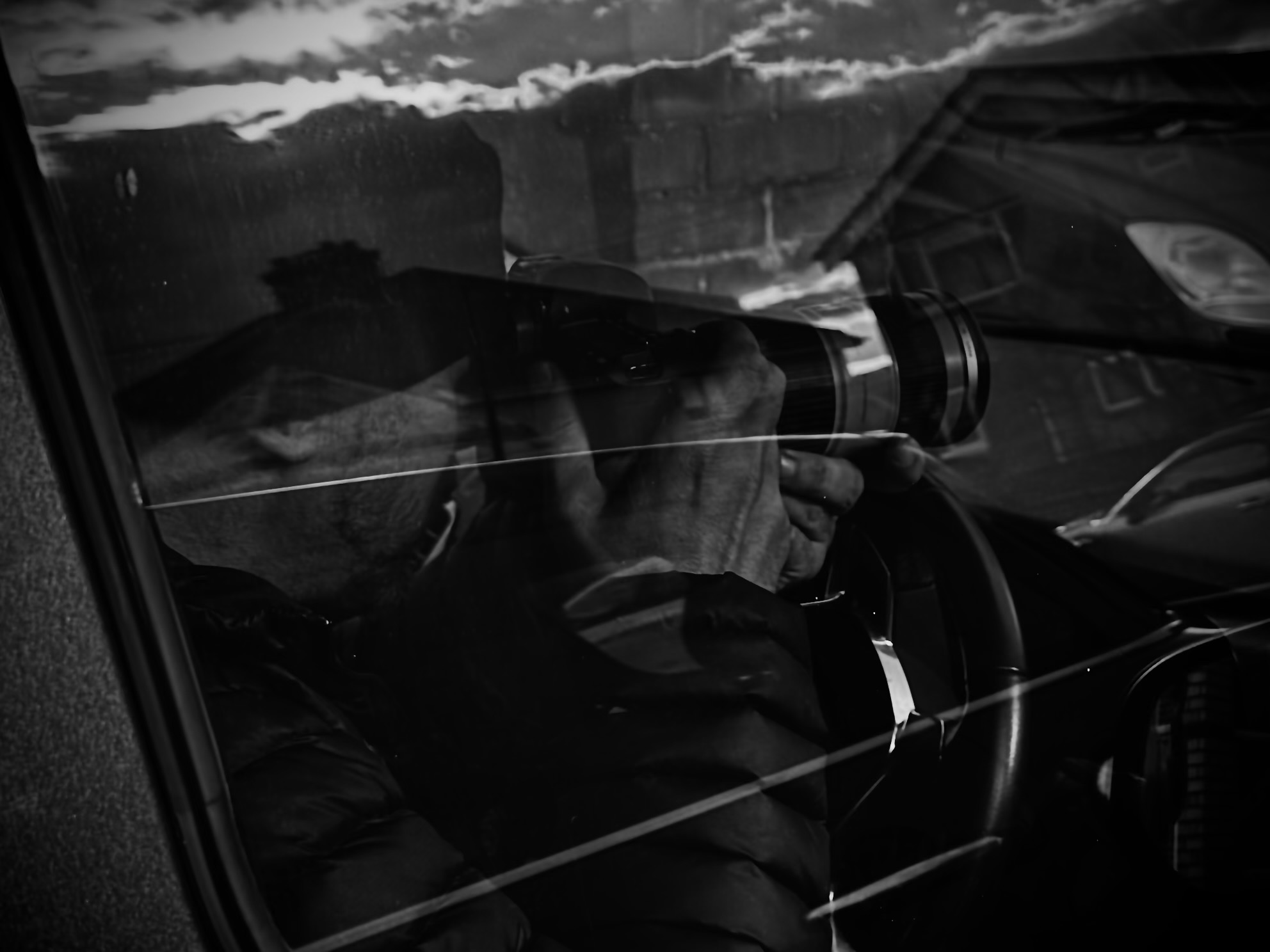 A surveillance operative discreetly photographing from inside a vehicle